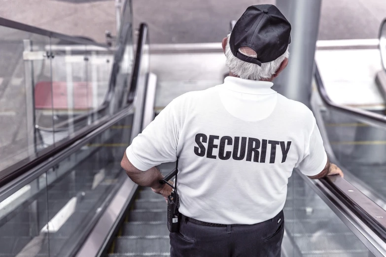 security man in uniform rides an escalator down the stairs