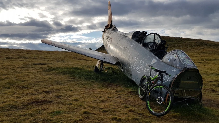 an old war plane sitting on top of a grassy hill