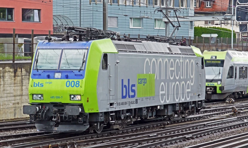 two trains on train tracks in front of buildings