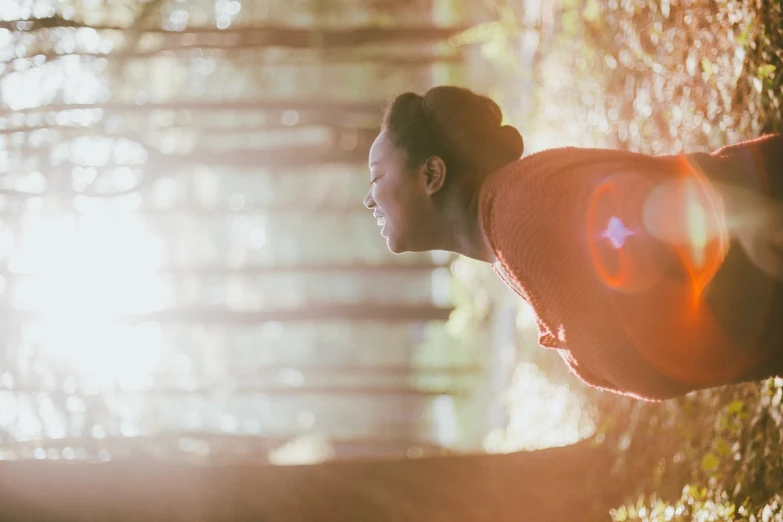 a woman with buns, wearing a sweater in the woods