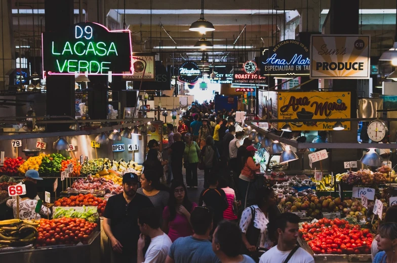 people are shopping in an indoor market with many vegetables