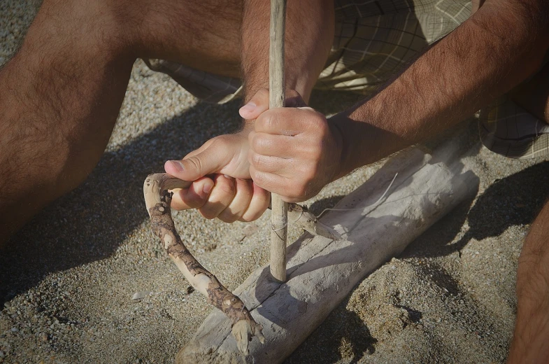 a hand holding an item in the sand