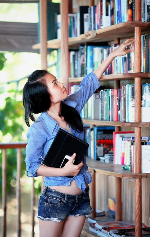 there is a woman holding an object near the bookshelves