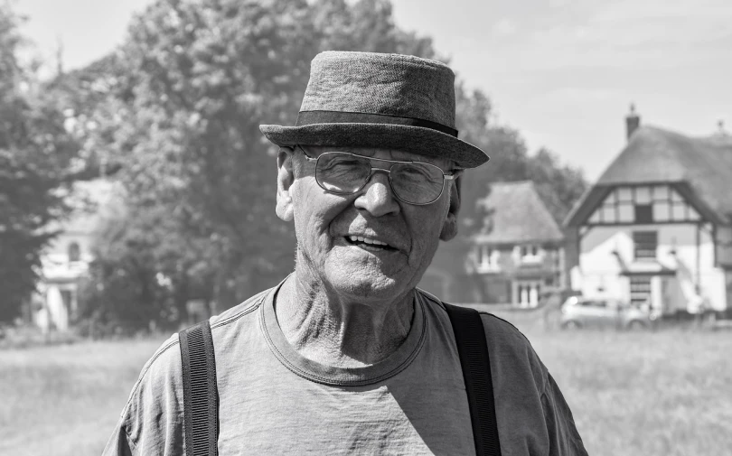 a man wearing glasses and a hat standing outside