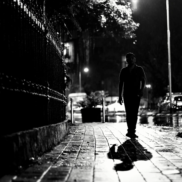 the man walks down the street at night in the rain