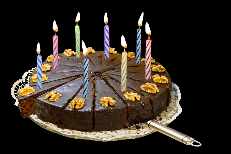 a chocolate cake with five candles and walnuts