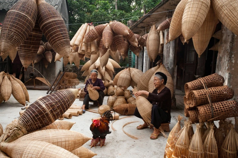 two women are sitting in front of many woven items