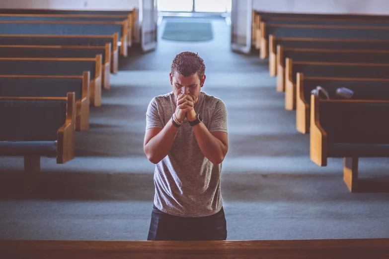 a man sitting in a pew while holding his hands up to their mouth