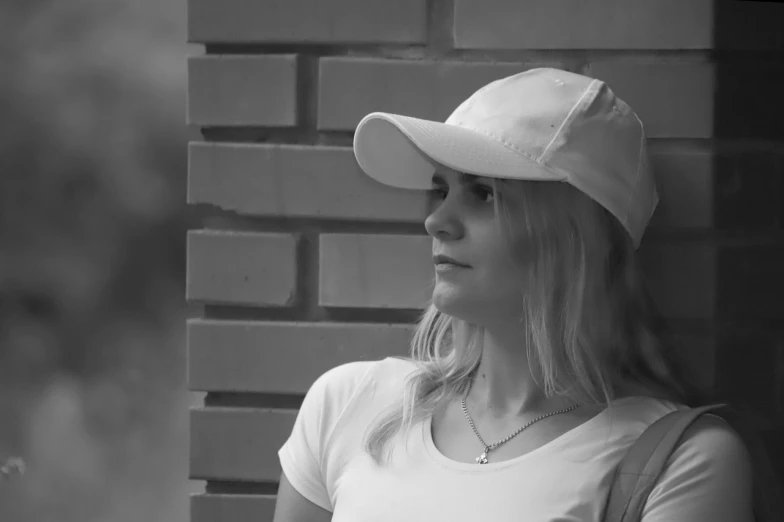 black and white pograph of woman wearing hat with brick wall