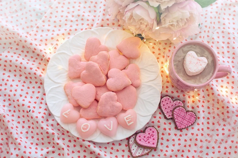 two cups, one heart - shaped cookies, and another heart - shaped conversation bubbles are placed on the table