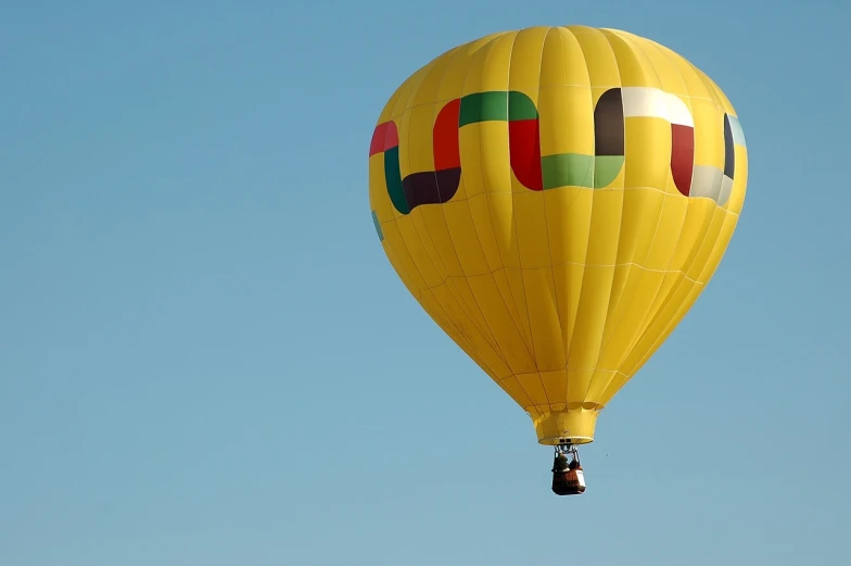 a bright yellow  air balloon is flying high in the sky