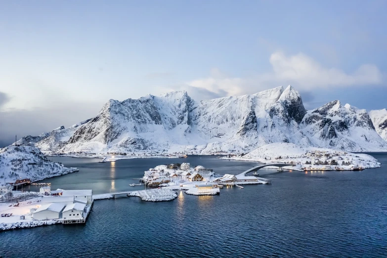 a snowy scene with mountains and boats in the water