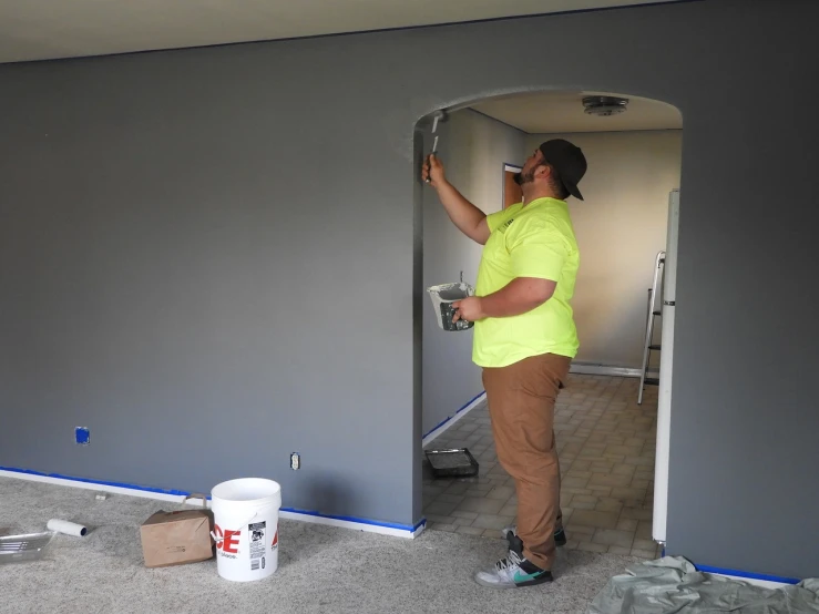 a man is putting paint on the walls of a room