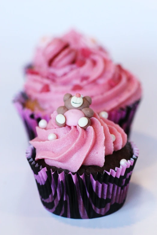 two cup cakes with pink and brown frosting