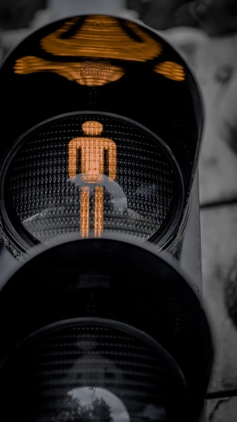 an orange man crossing sign and a black street light