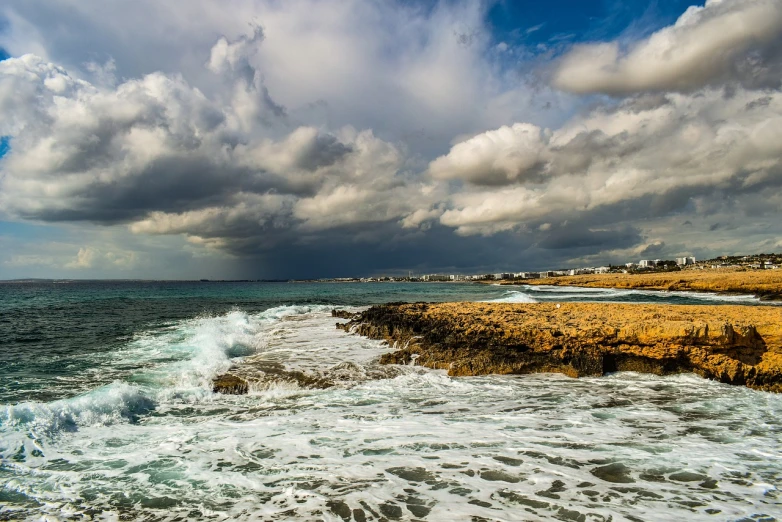 large waves coming in to shore with the beach covered by storm clouds