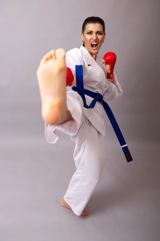 a woman in karate attire standing with a foot up