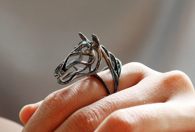 a person wearing a silver ring that is shaped like an origami horse