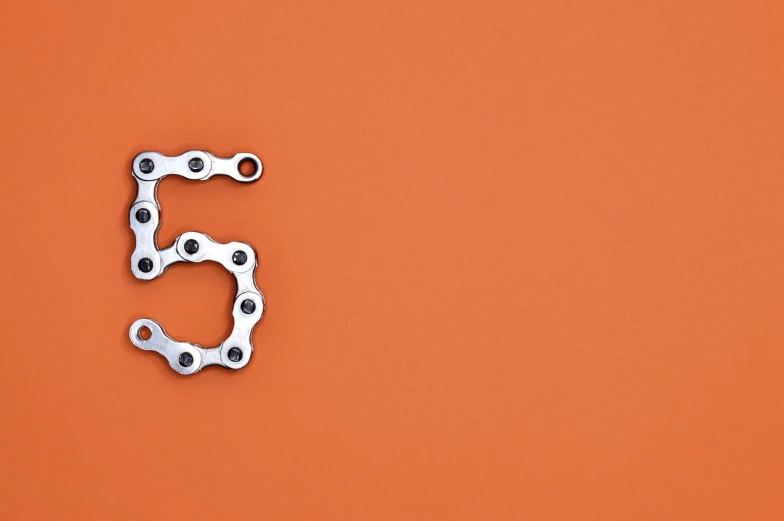 two silver gears with the number five against a burnt orange background