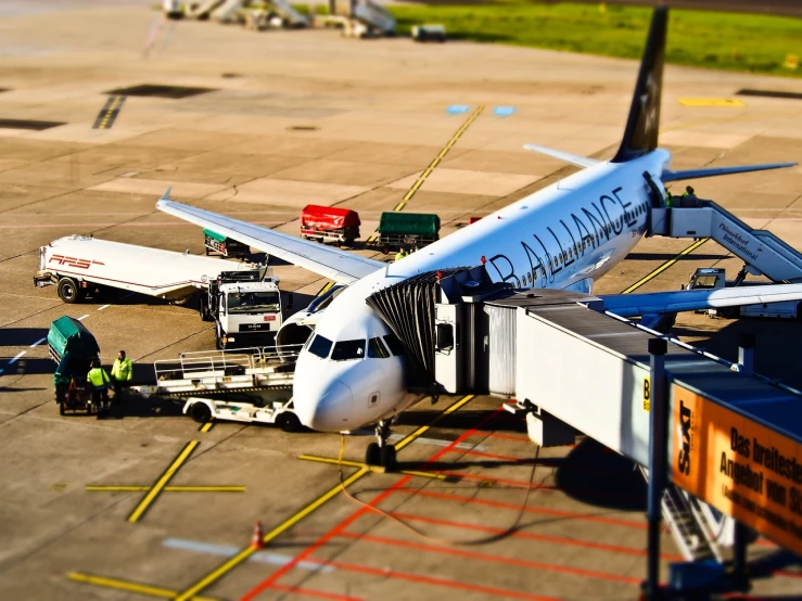 airplane parked on runway with worker near baggage handler