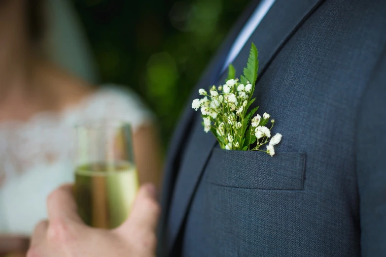 the groom is holding a small glass filled with baby's breath