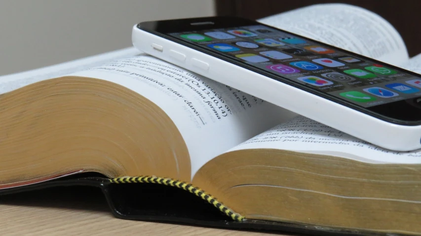 a smart phone is laying on top of a book