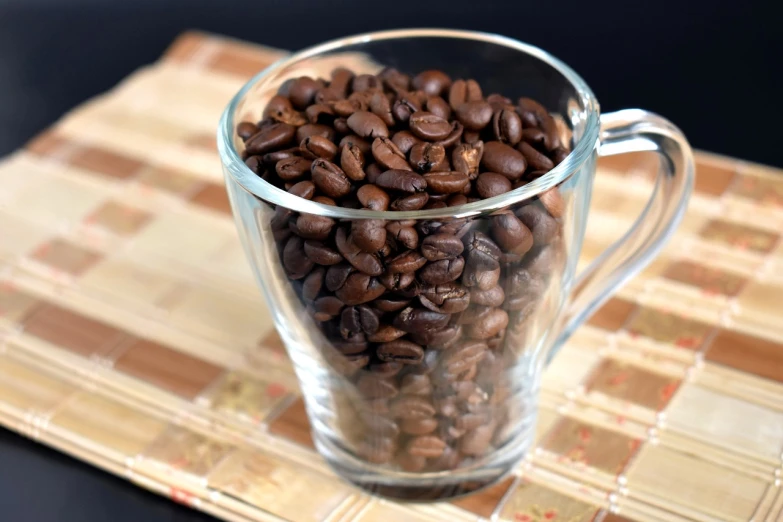 the glass mug is filled with brown coffee beans