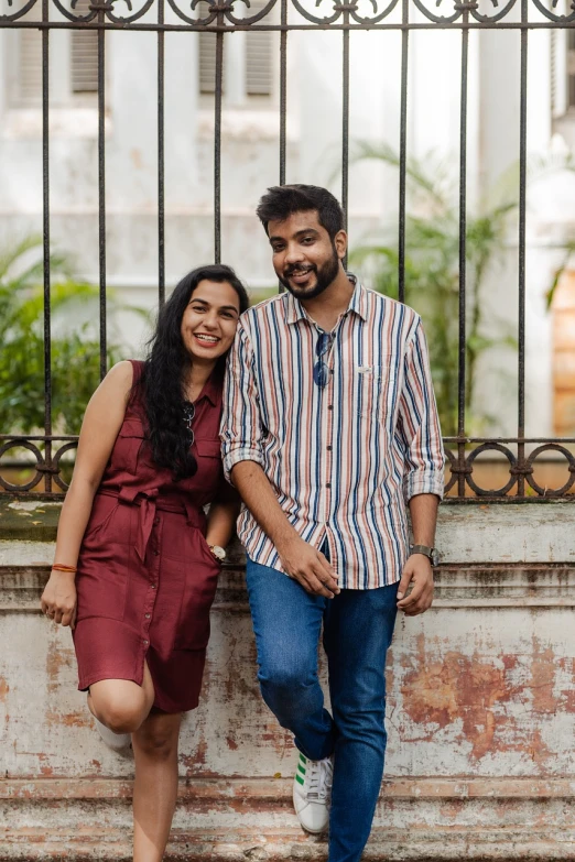 a couple posing for the camera in front of a iron gate