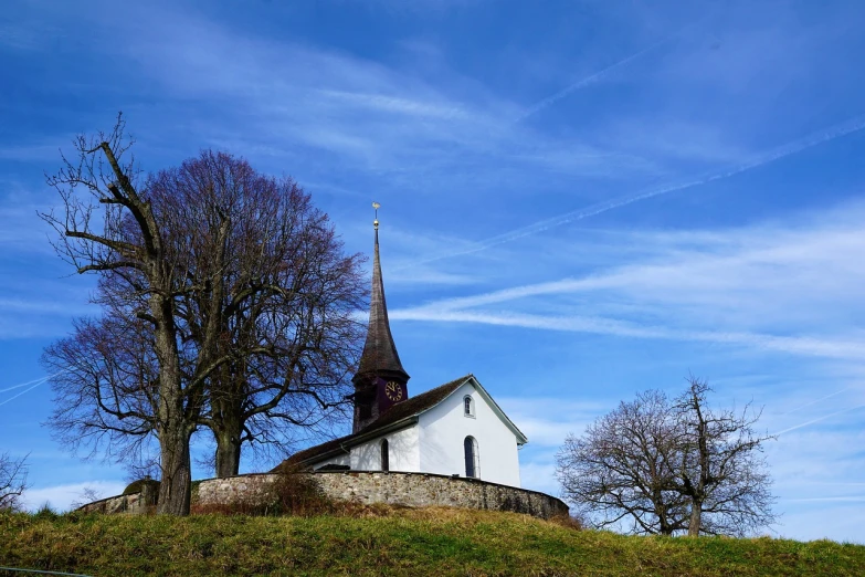 an old white church is perched atop a hill