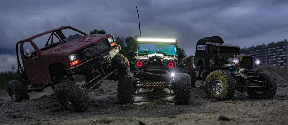 two trucks with four cars sitting next to each other in the dirt