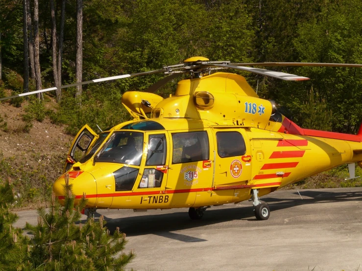 a yellow helicopter parked in front of trees