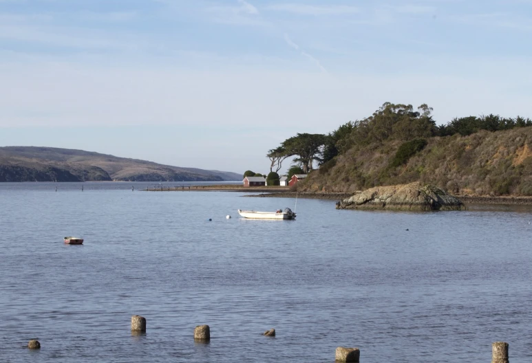 small boat sailing through the ocean water near land