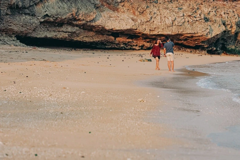 two people walk down the beach towards the water