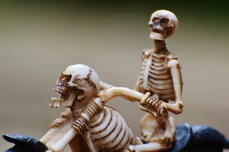 a figurine of two skeleton riding on a horse