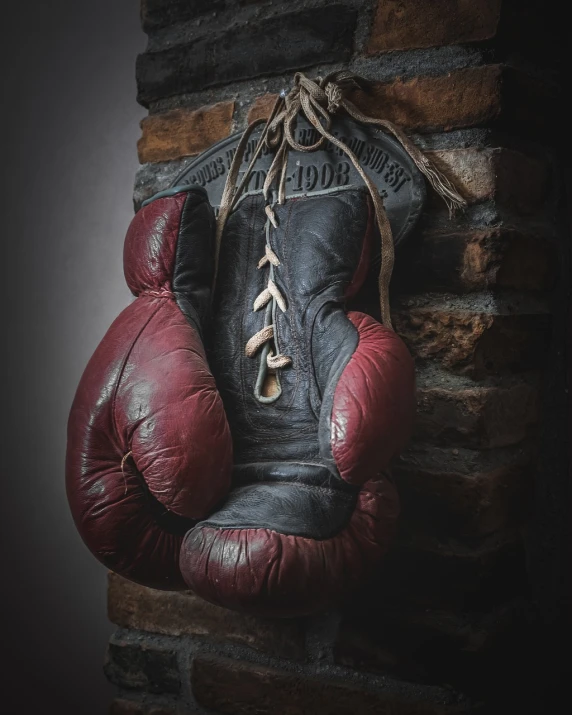 a leather boxing glove hanging from the side of a brick wall