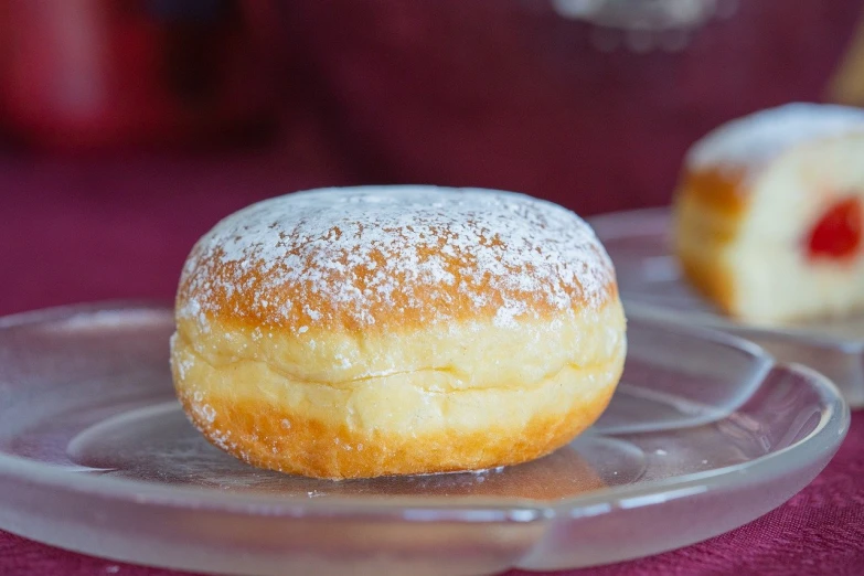 powdered sugar donuts on a plastic plate on a purple cloth