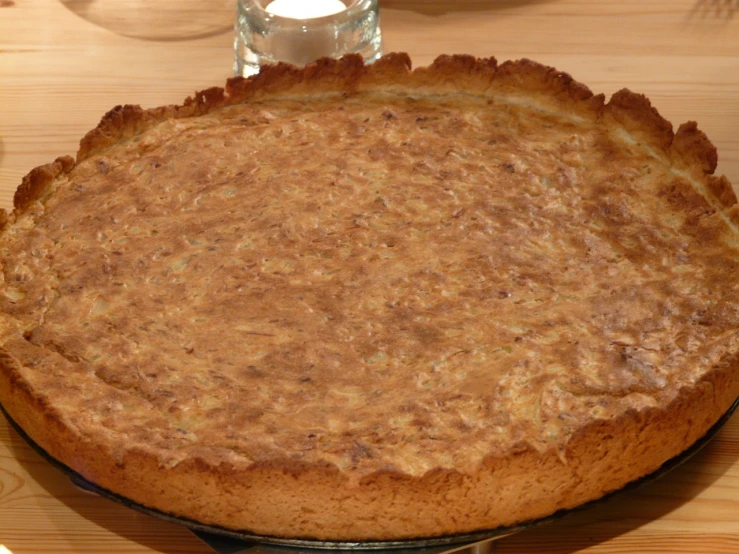 a pie on a tray with a candle on a table