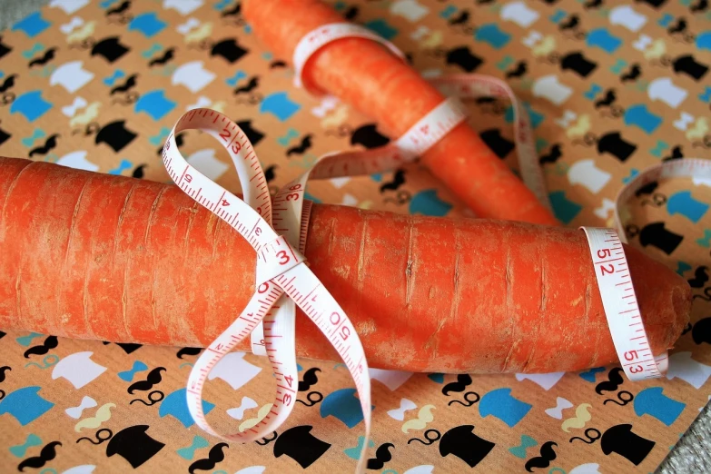 two carrots are wrapped with tape and two measuring tapes