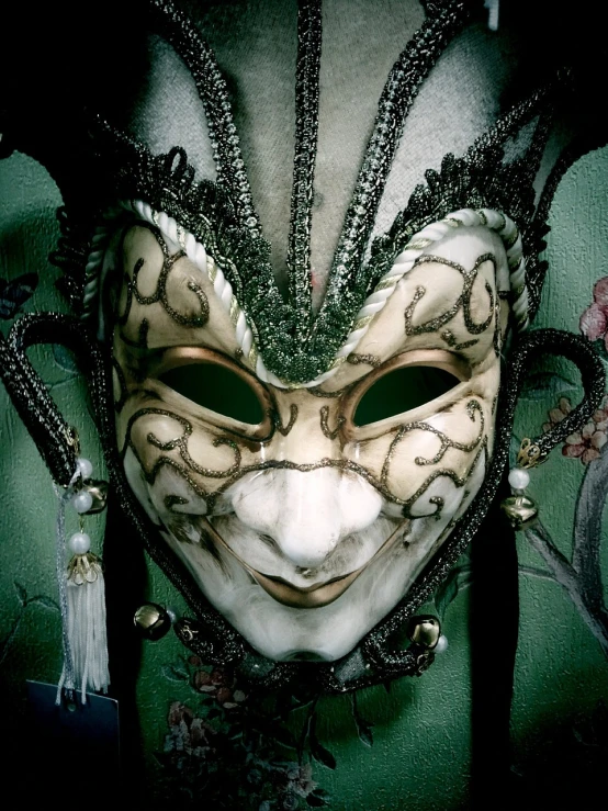 a mask with beads and an elaborate pattern is against a green wall