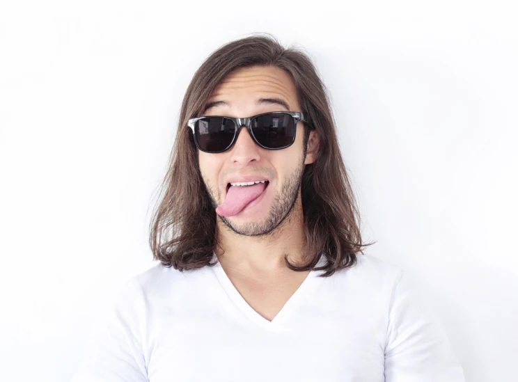 a young man with his tongue out with sunglasses on