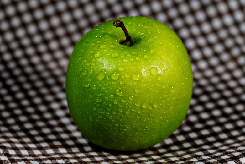 a green apple is on a black and white table cloth