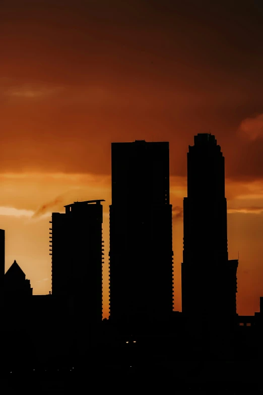 an airplane flying over some buildings under a red and blue sky