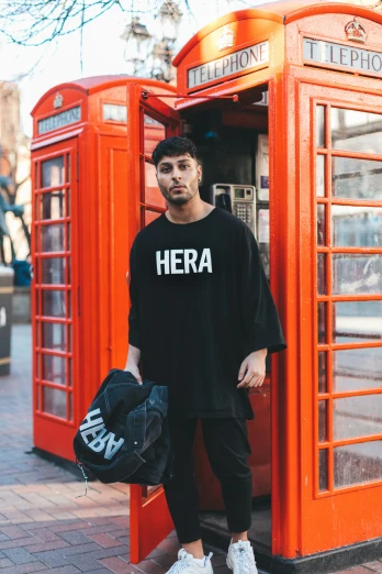 a man with his hand in his pocket stands next to some telephone booths