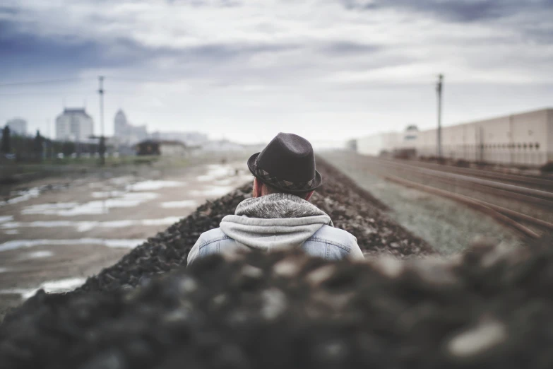 a person with a hood on standing near railroad tracks