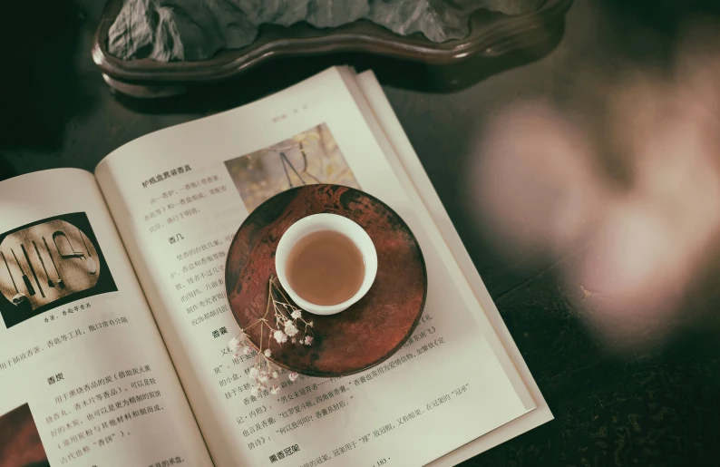 an open book that is next to a cup of coffee