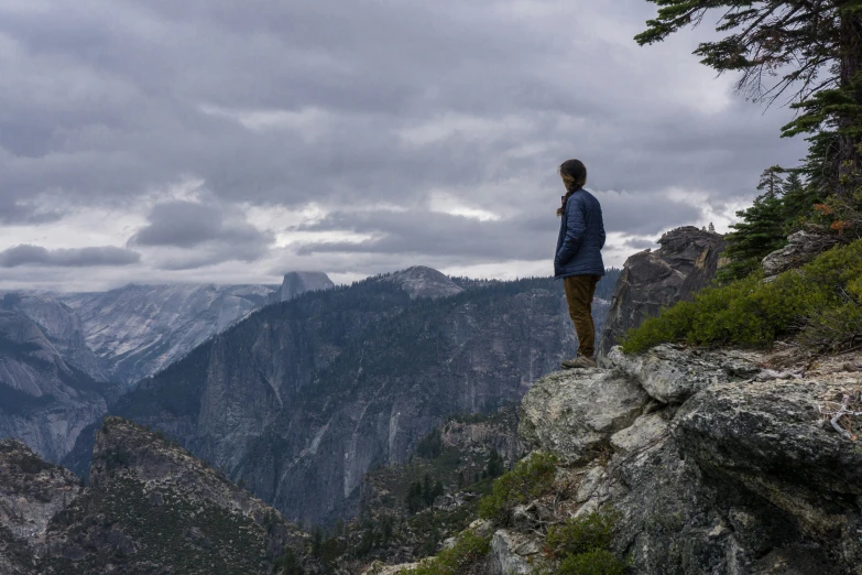 a man standing on the edge of a cliff overlooking mountains