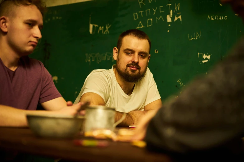 three men in front of a chalk board with writing on it