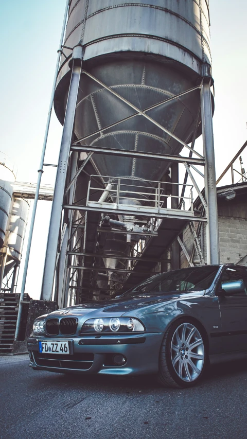 a blue car in front of a large water tower