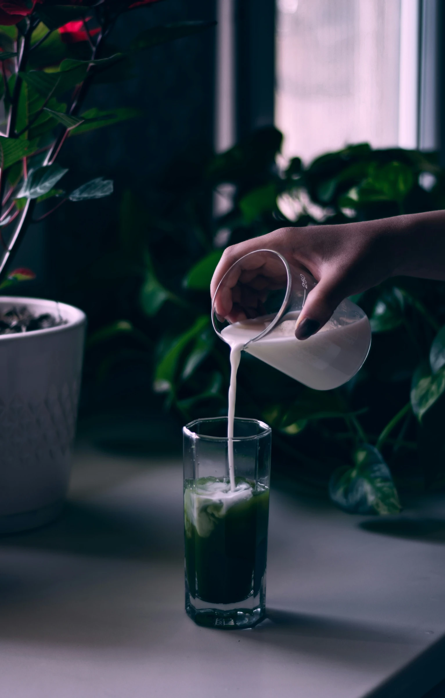 a person pouring a liquid into a glass on top of a table