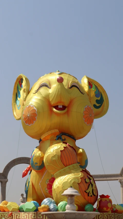 a large yellow rat balloon in the air